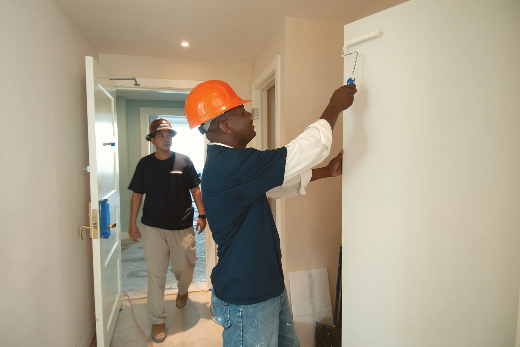 Two workers actively renovating a residential interior.